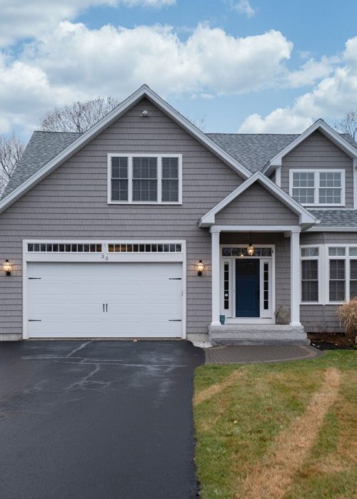 A gray-walled suburban house with white asphalt driveway