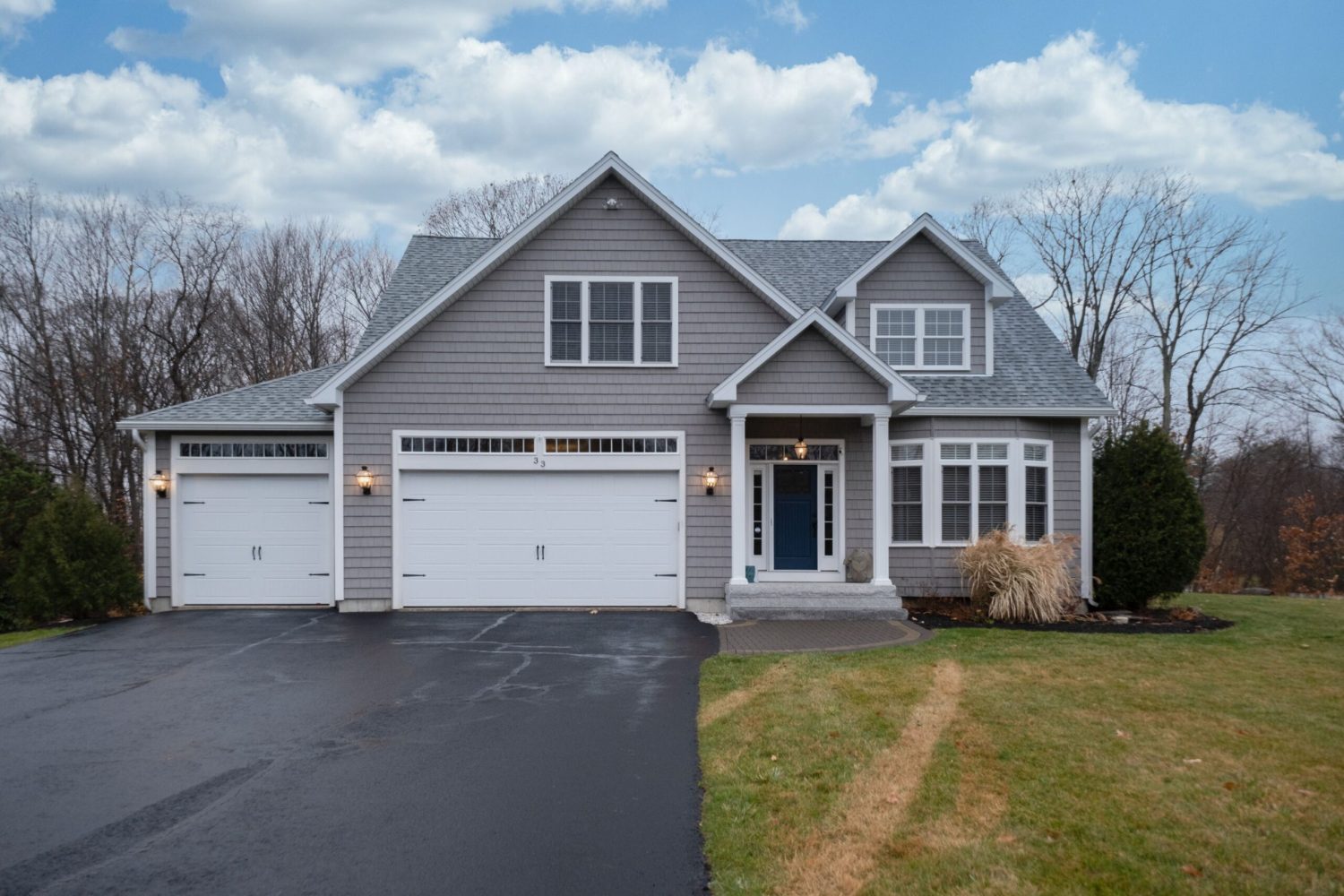 A gray-walled suburban house with white asphalt driveway