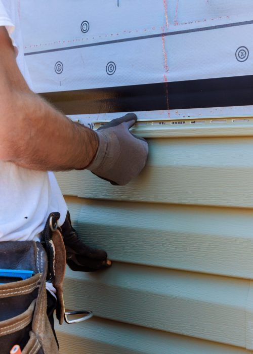 Handyman process installing vinyl PVC siding during construction on facade new home